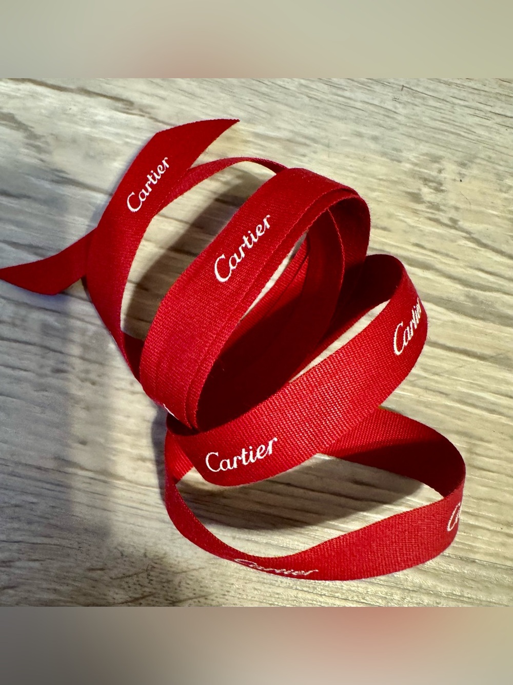 Cartier – Bright red textile ribbon featuring the repeating Cartier brand logo.